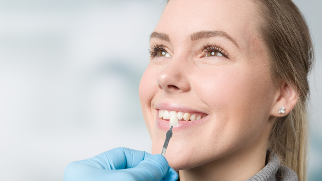 Smiling-woman-having-dental-veneers-color-matched-by-a-dentist-wearing-gloves
