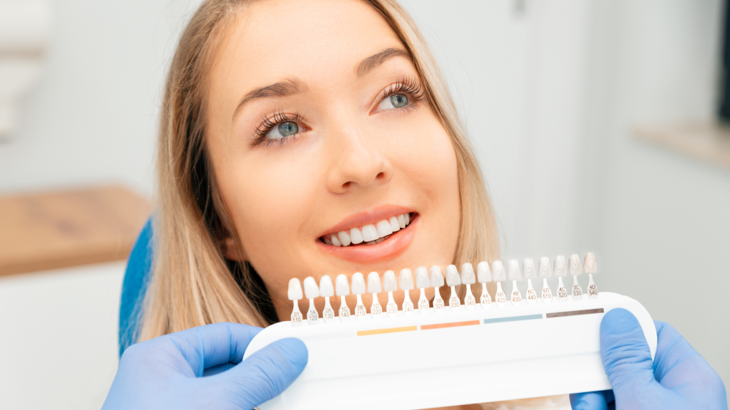 Woman at dental clinic selecting tooth shade for cosmetic veneers treatment